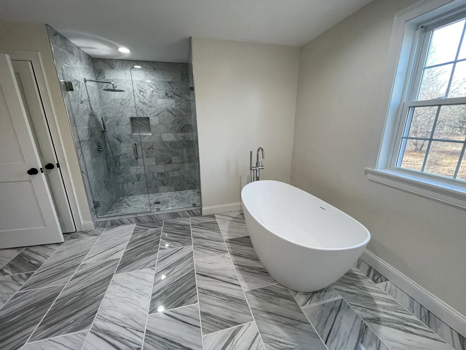 Freestanding tub, herringbone marble floor & glass shower